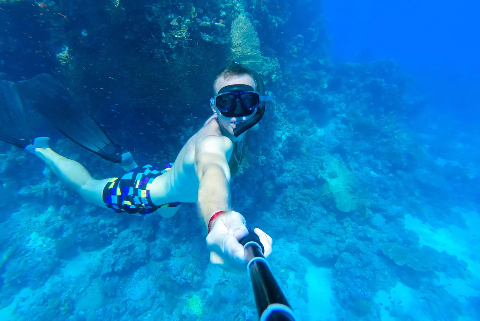 Snorkeler in mask and snorkel entering clear blue ocean water in Hawaii