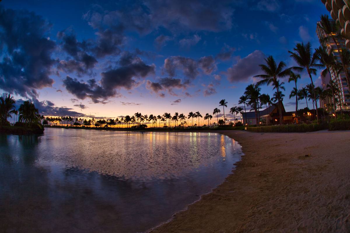 Sunset over Waikiki Beach in Honolulu, Oahu, Hawaii, with surfers in the water