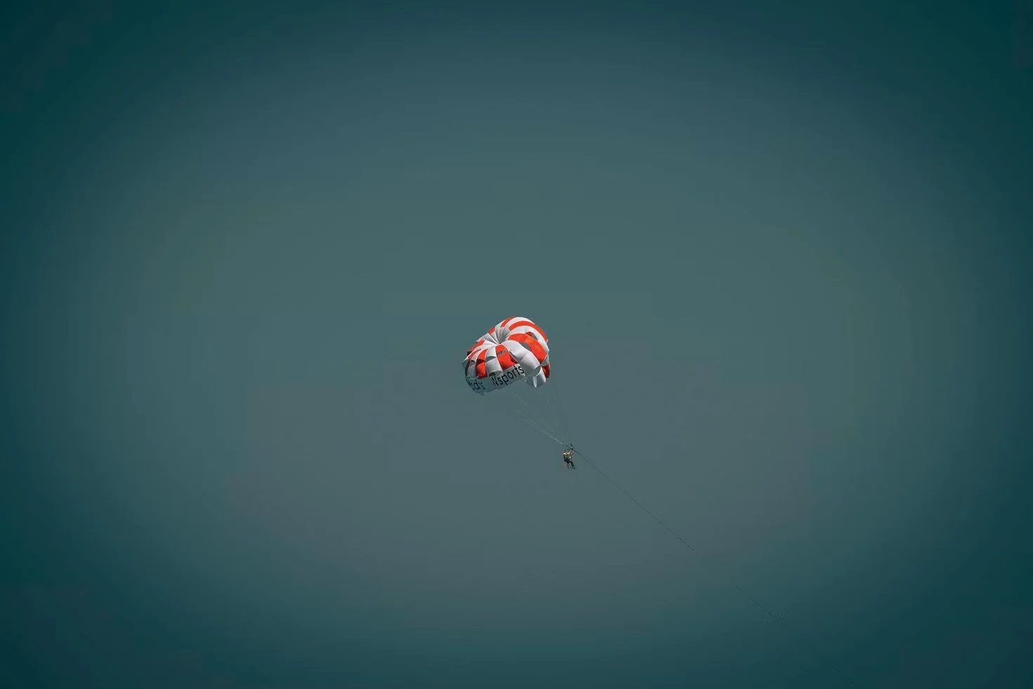 Parasail canopy in flight over the ocean, towing riders on a long line